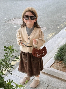 Outdoor street style showing crochet cat bag with knit cardigan and corduroy skirt
