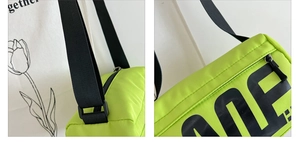 Détail du sac bandoulière en nylon vert néon avec lettrage noir et sangle ajustable