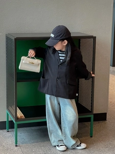 Detail view of the black kid's blazer and blue wide-leg jeans in minimalist Korean style