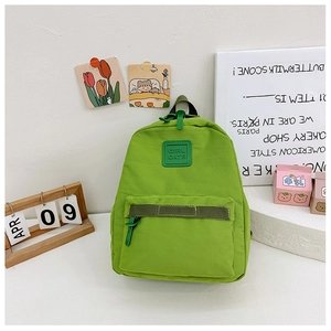 Detail eines grünen Canvas-Rucksacks mit Silikon-Logo und vorderer Reißverschlusstasche