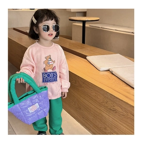 Détail d'un enfant portant un sac à bandoulière matelassé aux couleurs macaron et sweatshirt