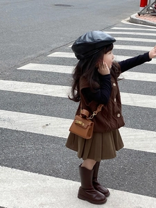 Outdoor city street view of kids brown mini leather handbag paired with autumn outfit