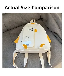 Size comparison of white cartoon penguin backpack with a smartphone on a gray sofa