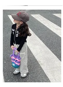 Tenue streetwear enfant avec sweat à capuche noir, pantalon rayé et sac en crochet