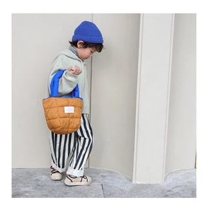 Détail d'un sac matelassé pour enfants avec poignées bleues et tissu en nylon marron