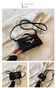 Detail of mini black lychee leather bag with gold buckle on white fabric