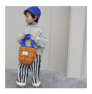 Détail du sac matelassé en nylon marron avec anses bleues contrastées pour enfants