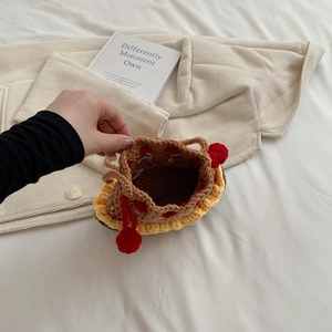 Cute handmade crochet hamburger drawstring bag with red pompom on a cozy home setting