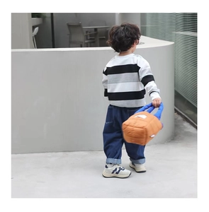 Sac à bandoulière matelassé en nylon marron et bleu porté par un enfant en extérieur