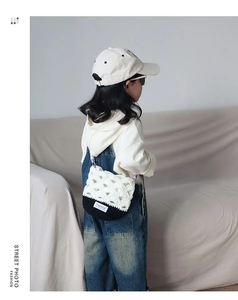 Gros plan d'un enfant portant le sac à bandoulière en crochet fait main noir et blanc