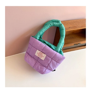 Détail d'un sac cabas matelassé avec poignées contrastées et étiquette de marque blanche