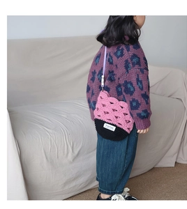 Détail du sac à bandoulière rose crocheté à la main avec design ajouré et étiquette tissée