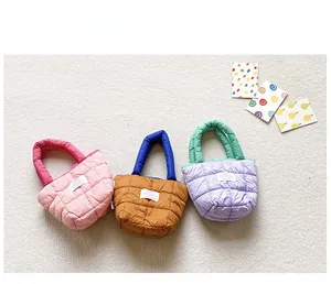 Gros plan de mini sacs matelassés aux tons pastel avec étiquettes sur un tapis moelleux