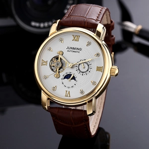 Detail of rose gold mechanical watch with Roman numerals and brown leather strap