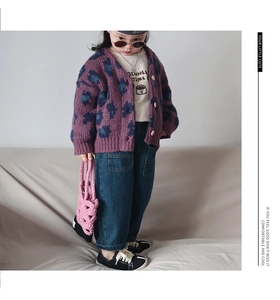 Détail d'un cardigan en tricot violet à fleurs avec un petit sac au crochet rose