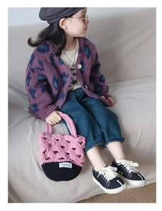Détail d'un sac au crochet rose et noir assorti d'un cardigan en maille violette