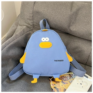 Detail of cute light blue cartoon chicken backpack on a gray sofa with lifestyle props