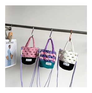 Détail de mini sacs seaux au crochet faits main avec bandoulières et motifs floraux