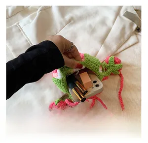 Macro view of hand-knitted strawberry bag interior holding a smartphone and lipsticks
