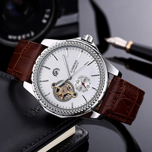 Macro detail of men's automatic watch with white dial and brown leather strap on a desk