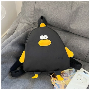 Detail view of the TOCHASO cartoon penguin backpack with yellow beak on a grey sofa