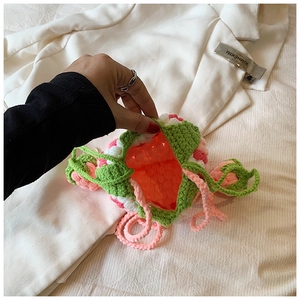 Close-up of handmade pink crochet strawberry bag with drawstring on neutral background