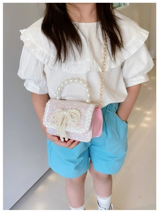 Detail of pink tweed girl's bag with pearl bow, handle and gold chain strap shown on model