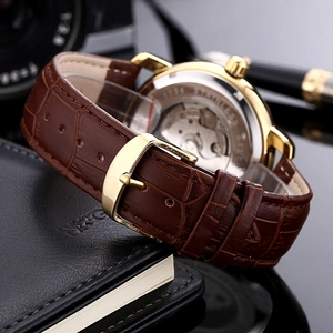 Detailed macro view of the brown leather strap and high-gloss gold buckle on a watch