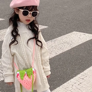 Detailed knit texture of a handmade pink strawberry crochet bag on a young model