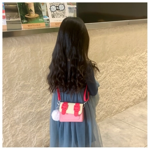 Détail du sac bandoulière rose et crème pour enfants avec un pompon en peluche blanche
