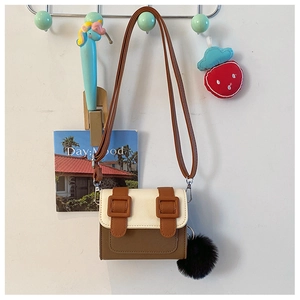 Détail du mini sac bicolore avec boucles décoratives et pompon noir suspendu