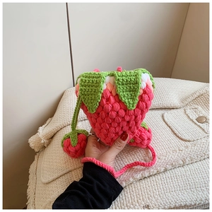 Detail of handmade crochet strawberry bag with green leaf top and matching berry charms