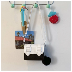 Détail du sac bandoulière bicolore noir et blanc avec pompon et sangles décoratives