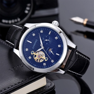 Business watch with blue sunray dial and leather strap on a notebook with camera gear
