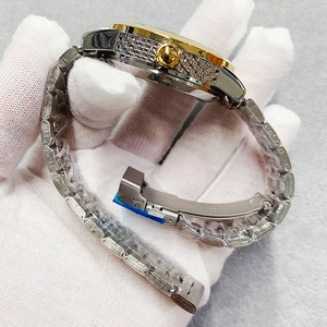 Close-up of stainless steel watch band with side-set cubic zirconia and golden bezel