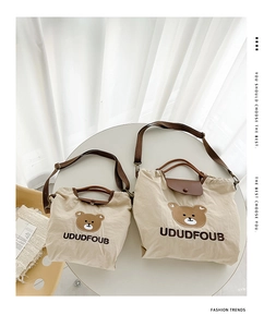 Detail of beige canvas kids bags in two sizes with bear embroidery and adjustable straps