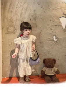Detail of cream girls' two-piece set featuring hollow embroidery and ruffled sleeves