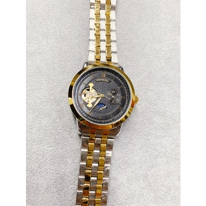 Close-up of the mechanical dial with golden Roman numerals and steel band