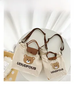 Close-up of two beige canvas tote bags with bear embroidery and leather handles