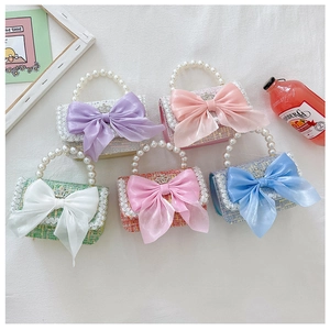 Detail of tweed girls' bags with organza bows and pearl handles in multiple pastel colors