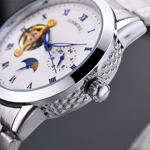Macro detail of silver stainless steel case and white texture dial with blue Breguet hands