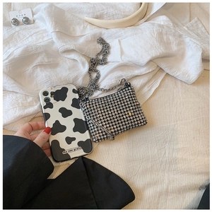 Close-up of sparkling silver rhinestone mini bag with elegant metal chain and cow print phone case