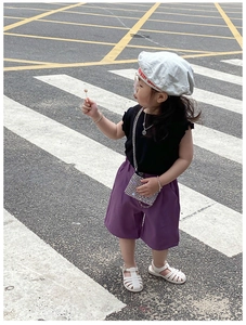 Detailed street style view of a girls black top and purple wide-leg shorts outfit