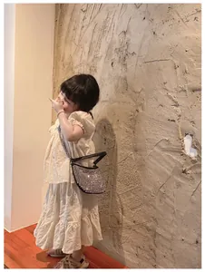 Detail of girl's cream puff sleeve top with floral embroidery and rhinestone mini bag