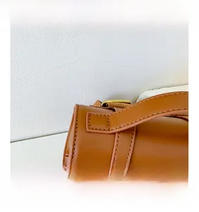 Detail of brown PU leather backpack showing precise stitching and brass metal buckles