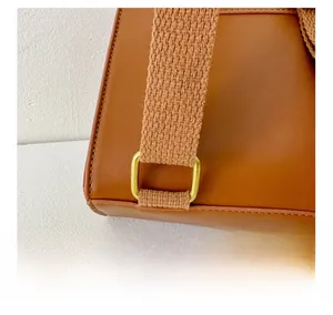 Macro detail of brown PU leather bag showing durable strap connection and gold metal buckle