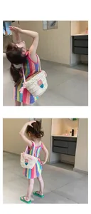 Detail of girls straw woven handbag featuring floral applique and pink rope handles