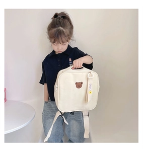 Détail de la broderie ours et ruban décoratif sur le sac à dos en toile crème enfant