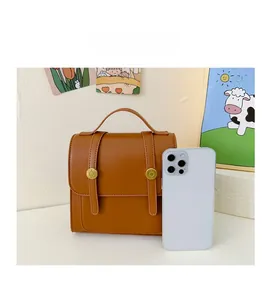 Size comparison of the brown vintage PU leather kids backpack next to a smartphone