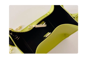 Detail shot of neon yellow kids' bag showing black lining and gold buckle closure